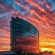 a dominating, sleek pharmaceutical building rises against a vibrant sunset, symbolizing the powerful monopoly in the medicine industry, with reflective glass panels conveying innovation and progress.