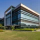 a sleek, modern pharmaceutical facility in chandigarh, bathed in warm afternoon sunlight, showcases its gleaming glass façade and green surroundings, emphasizing innovation and dedication to health.